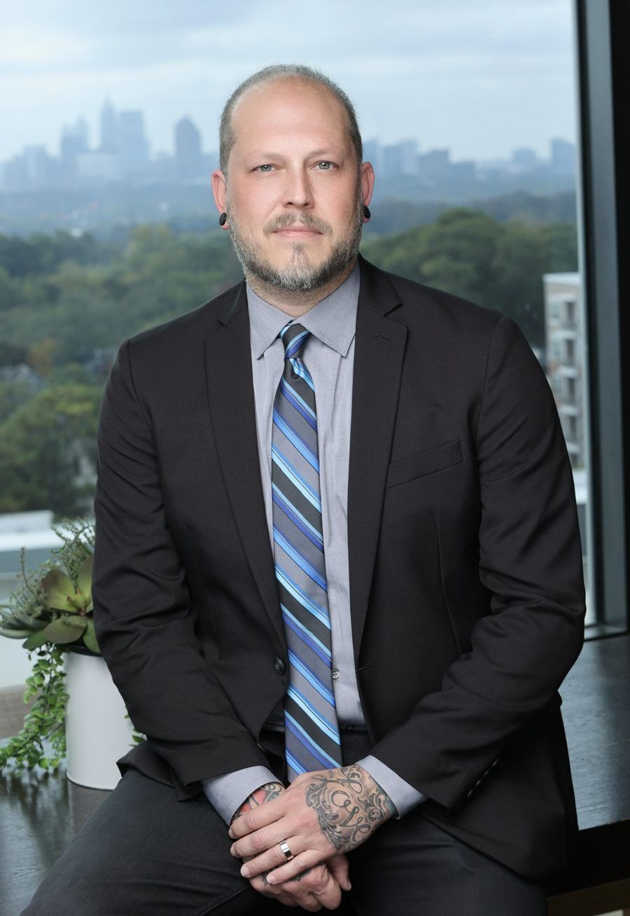Drew in a suit and tie with the Atlanta skyline behind him